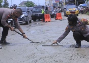 Anggota Polres Kupang Kota, Nusa Tenggara Timur, tambal sejumlah ruas jalan berlubang guna antisipasi dari kecelakaan lalu lintas